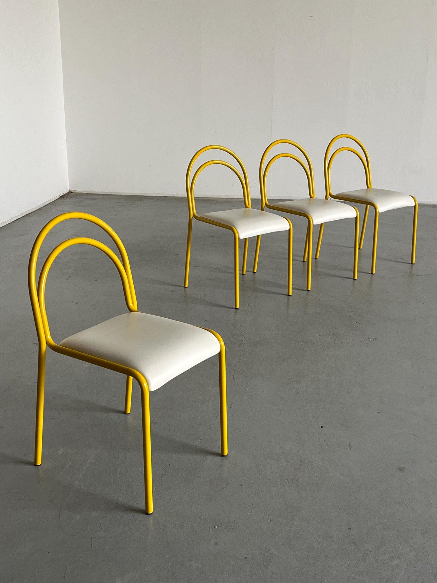 Ensemble de 4 chaises sculpturales avec structure en fer courbé jaune et revêtement en simili cuir blanc, Italie 1980