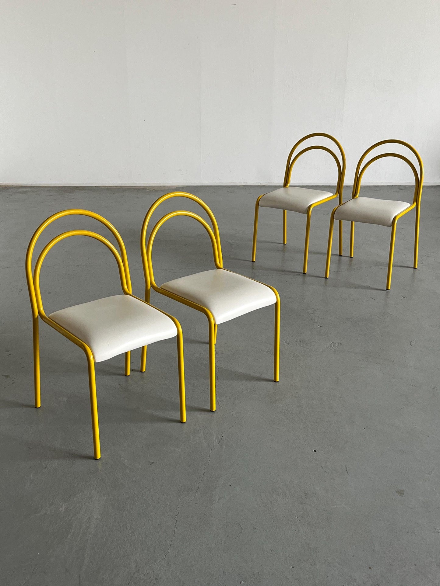 Ensemble de 4 chaises sculpturales avec structure en fer courbé jaune et revêtement en simili cuir blanc, Italie 1980